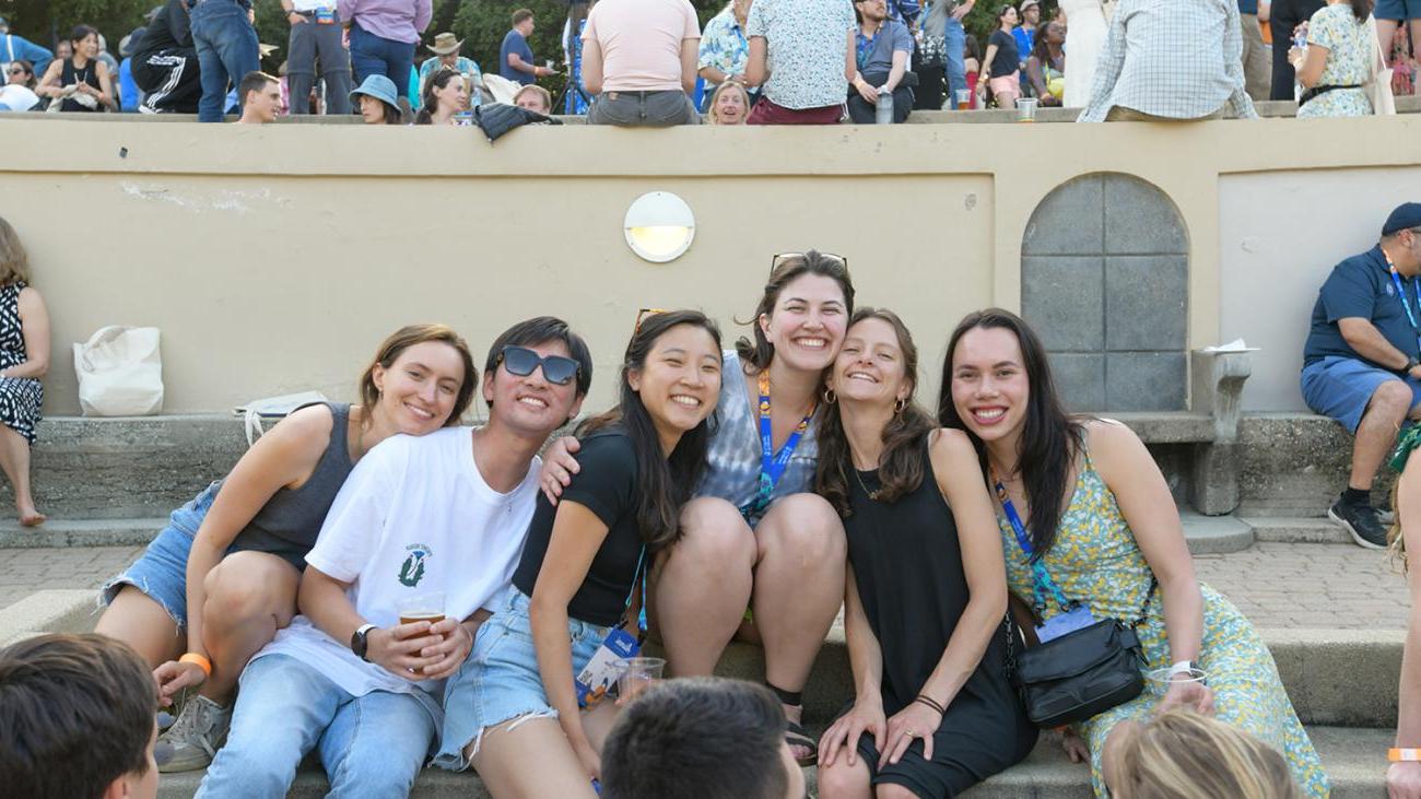 A group of alumni sit together and smile