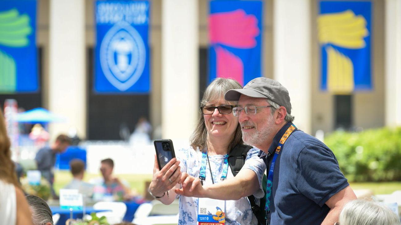 Two alumni take a picture in front of Pomona College banners